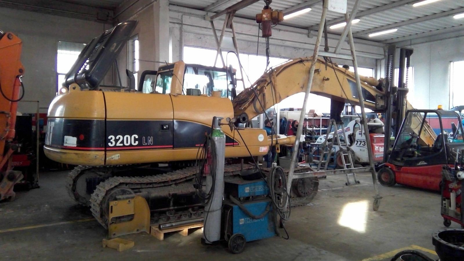 Un escavatore Caterpillar 320C sollevato sui cavalletti dentro l'officina.