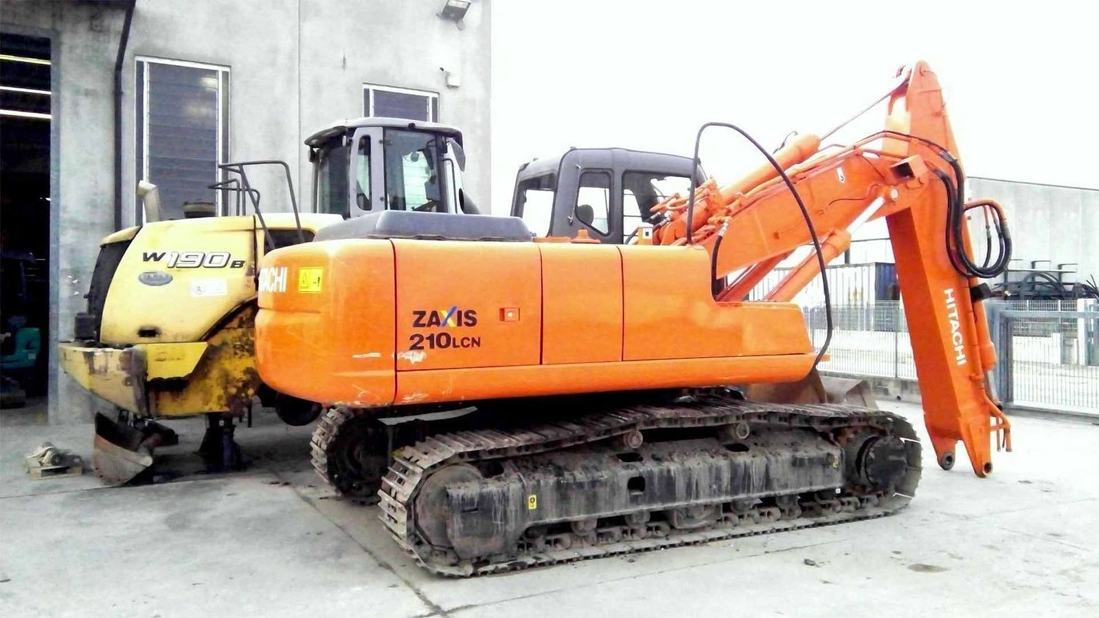 Un escavatore Hitachi ZAXIS accanto alla pala gommata New Holland W130.