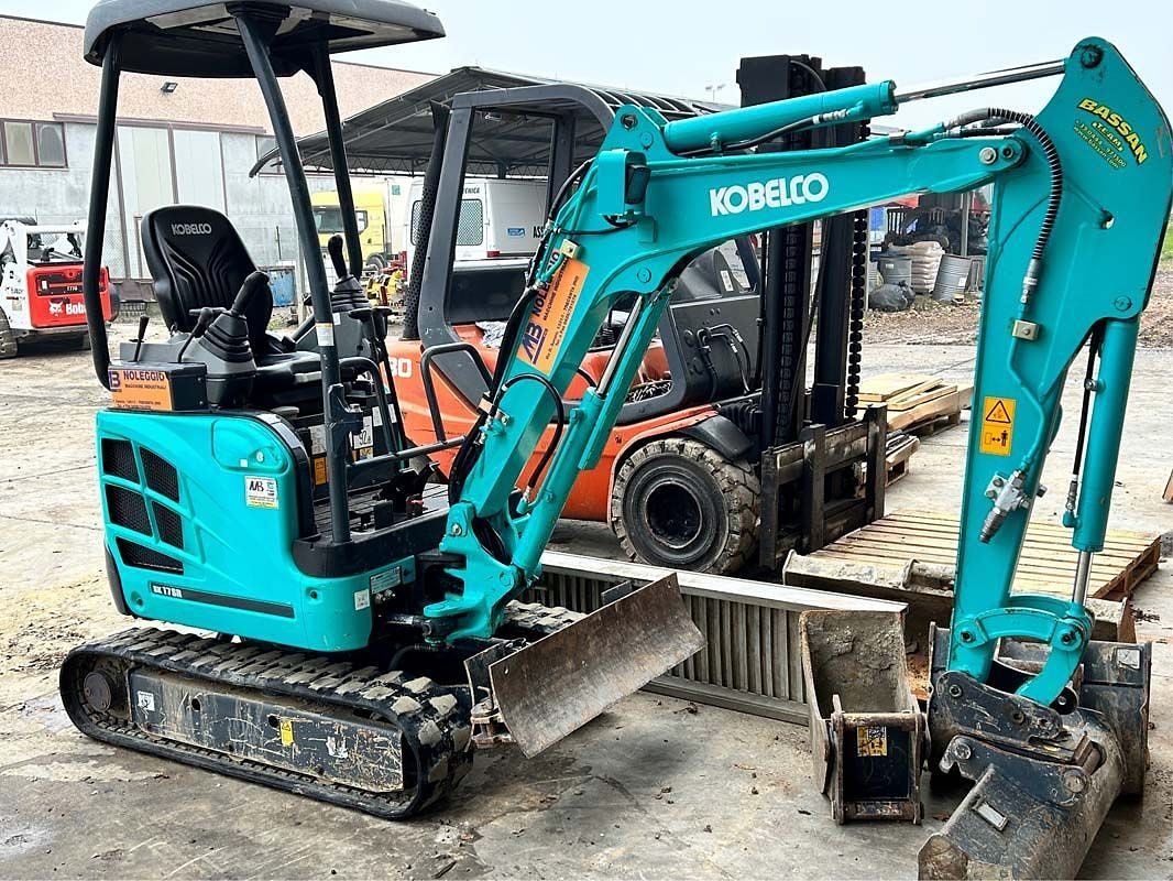 Una pala gommata New Holland accanto agli pneumatici di ricambio nel piazzale dell'officina.