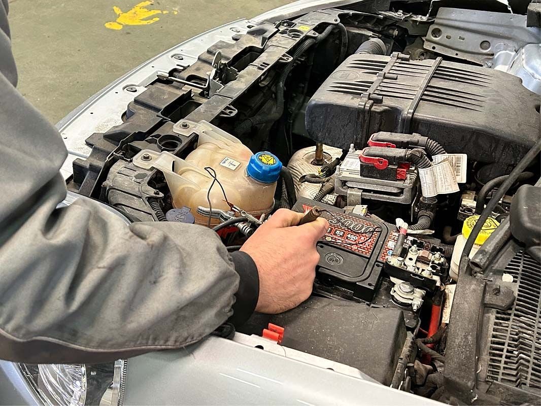Un tecnico dell'officina al lavoro sul vano motore con la strumentazione di diagnosi.