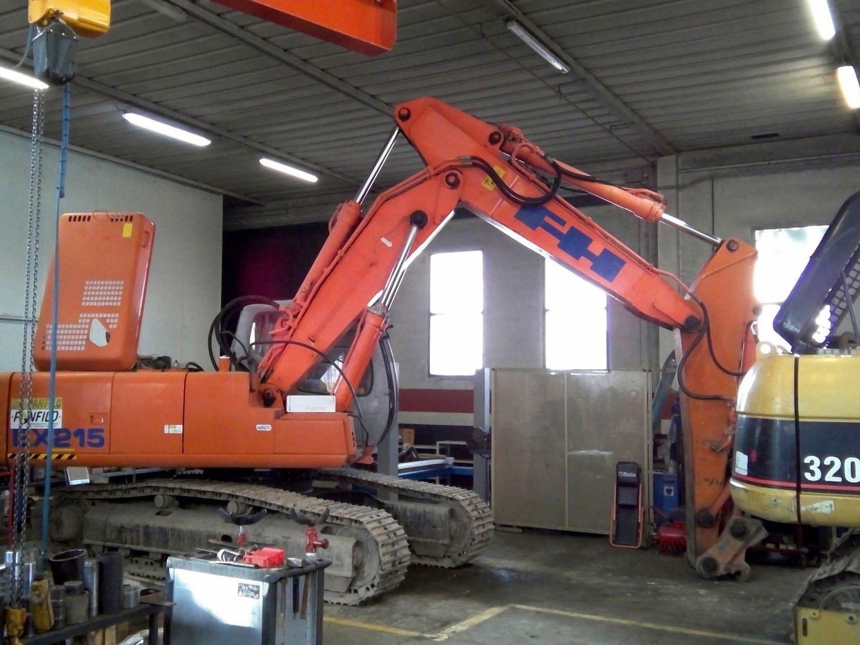 Il capannone dell'officina con un escavatore cingolato sollevato sui cavalletti per la revisione.