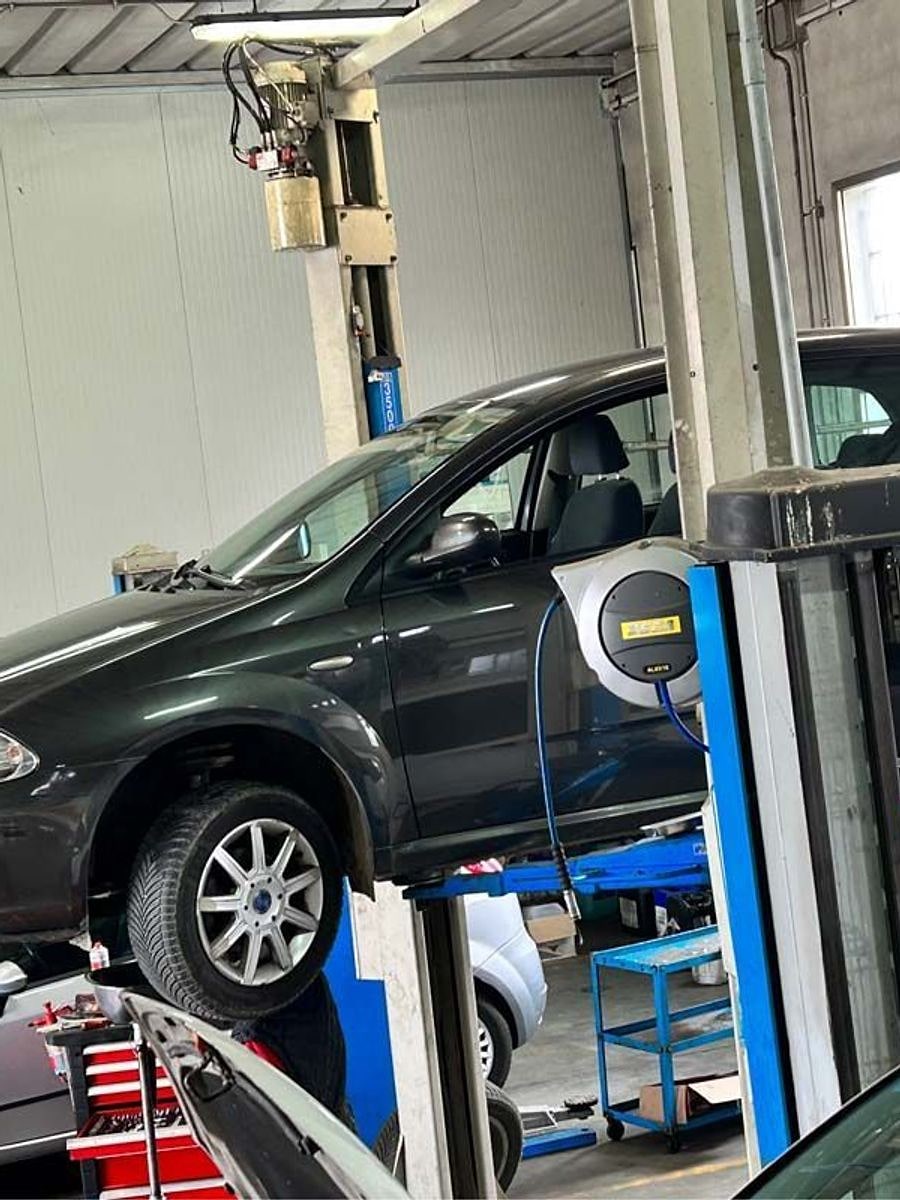 Due vetture sui ponti dell'officina durante il tagliando e la revisione.